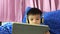 Asian child is wearing a headphone and watching cartoon on tablet.