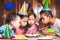 Asian children girls and boys celebrating birthday and blowing candles on birthday cake in the party together