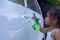 Asian children spry soap to clean car door handle