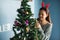 Asian Chinese happy girl with reindeer costume decorate gifts on Xmas tree. Attractive cute woman celebrate Christmas holiday in