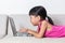 Asian Chinese little girl laying on sofa using laptop