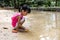 Asian Chinese little girl playing toy boat at creek