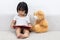 Asian Chinese little girl reading book with teddy bear