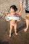 Asian Chinese little girl stepping into sea water with mom