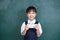 Asian Chinese little Girl in uniform playing digital tablet against green blackboard
