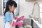 Asian Chinese little girl washing dishes in the kitchen