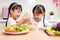 Asian Chinese little sisters making salad in the kitchen