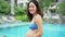 Asian Chinese pregnant woman mother holding her belly by the swimming pool