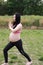 Asian Chinese pregnant woman in yoga dress do yoga meditation stand on grass in forest sunset enjoy free life