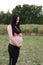 Asian Chinese pregnant woman in yoga dress in nature forest meditation do exercise workout look at belly hands on belly