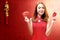 Asian Chinese woman in a cheongsam dress holding a credit card and red envelopes