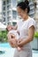 Asian chinese young mother carrying newborn child at her home swimming pool