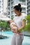 Asian chinese young mother carrying newborn child at her home swimming pool