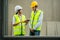 Asian Colleagues worker Specialists team wearing protective safety hard hat helmet use tablet on Construction Site. Civil Engineer