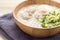 Asian congee with minced pork and egg in white bowl.