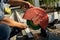 Asian Construction worker is sharpening chisel by big blade machine at outdoor field with tree in the row background