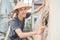 Asian construction workers smile at the camera wearing a hat while using a scoop to spread the cement