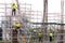 asian construction workers working on scaffolding of building construction site in city. urban expansion in  capital city of asia