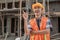 An Asian contractor stands wearing a safety helmet and vest with a gesture of getting an idea