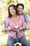 Asian couple both sitting on one bicycle in park