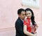 Asian couple in chinese style dress hold each other agianst pink wall