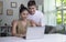 Asian couple communicating online on laptop. Loving Woman and Man embracing watching movie webinar on laptop studying e-learning