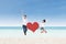 Asian couple jumping with heart card at beach