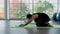 Asian couple practice yoga Adho Mukha Sawastikasana pose in glass room.