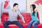 Asian couple quarreling on the red couch