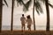 Asian couple is running and holding hands on a beachfront beach sea with coconut trees while on vacation in the summer in Thailand