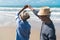 Asian couple senior elder retire resting relax dancing at sunset beach honeymoon