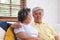 Asian couple senior embracing and sitting comfortably on sofa and  talking in living room at home