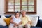 Asian couple senior embracing and sitting comfortably on sofa and watching tv in living room at home.