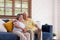 Asian couple senior embracing and sitting comfortably on sofa and  watching tv in living room at home.