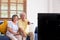 Asian couple senior sitting on sofa and use remote control to change channel and watching tv in living room at home.panning from