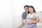 Asian couple sitting and embracing wife 8 months tummy, smiling to the camera. Family waiting for newborn baby