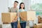 Asian couple standing with moving cardboard boxes