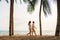 Asian couple is walking and holding hands on a beachfront beach sea with coconut trees while on vacation in the summer in Thailand