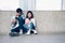 Asian couples of happy smiling sitting using smartphone in covered walkway.