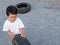 Asian cute child boy playing auto car tire wheel with smiling face,  copy space for advertising message.