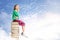 Asian cute girl with glasses think while sitting on the pile of books with blue sky background