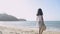 Asian cute girl holding straw hat wearing casual dress standing on the beach under sunlight in the morning.