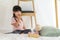 Asian cute little girl eating snack while sitting in a blanket fort in living room at home for perfect hideout away from their