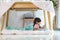 Asian cute little girl watching cartoon in smartphone while lying in a blanket fort in living room at home for perfect hideout