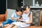 Asian cute sibling child using a smartphone and smiling for watching video or play game togerther while sitting on sofa in living