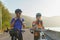 Asian cyclist couple dons helmets and chin straps as they prepare for their bike ride around a beautiful morning lake