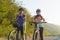 Asian cyclist couple dons helmets and chin straps as they prepare for their bike ride around a beautiful morning lake