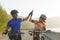 Asian cyclist couple highfive together after cycling to their destination around a lake in the morning with beautiful mountains in