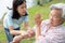 Asian daughter or caregiver hand pouring medicine pills or capsules from bottle,giving pills to senior grandmother in wheelchair