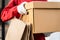 An Asian deliver man in red uniform handing parcel to a female costumer in front of the house. A postman and express delivery